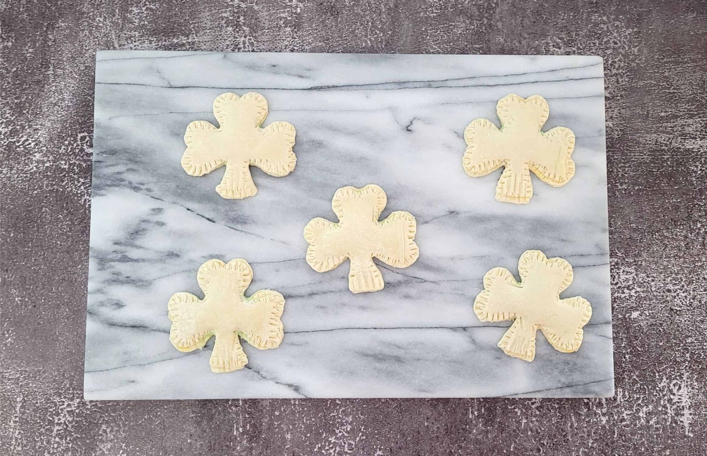 sealed edges of puff pastry shamrocks using a fork