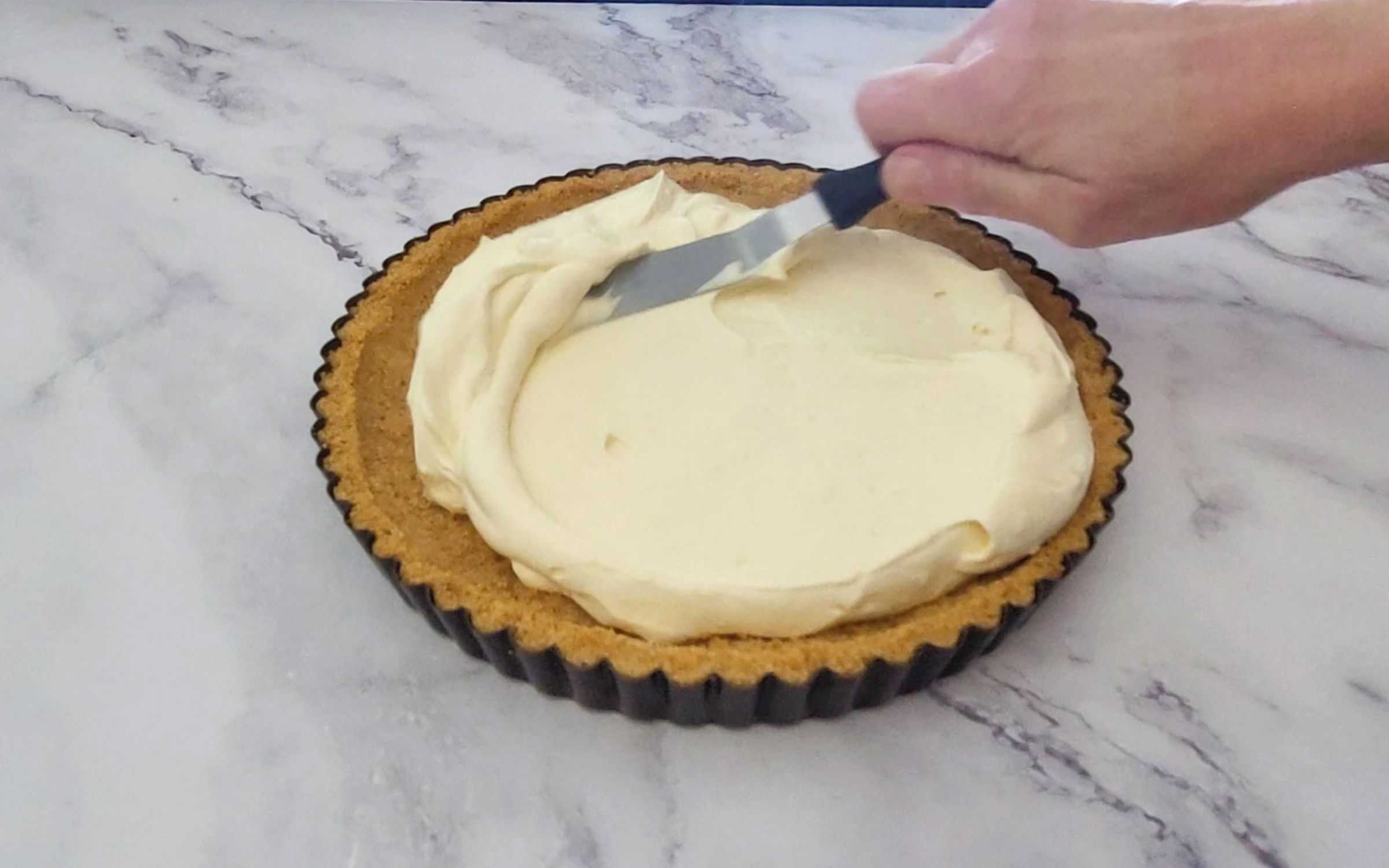 spreading lemon cream filling into pie crust using an offset spatula