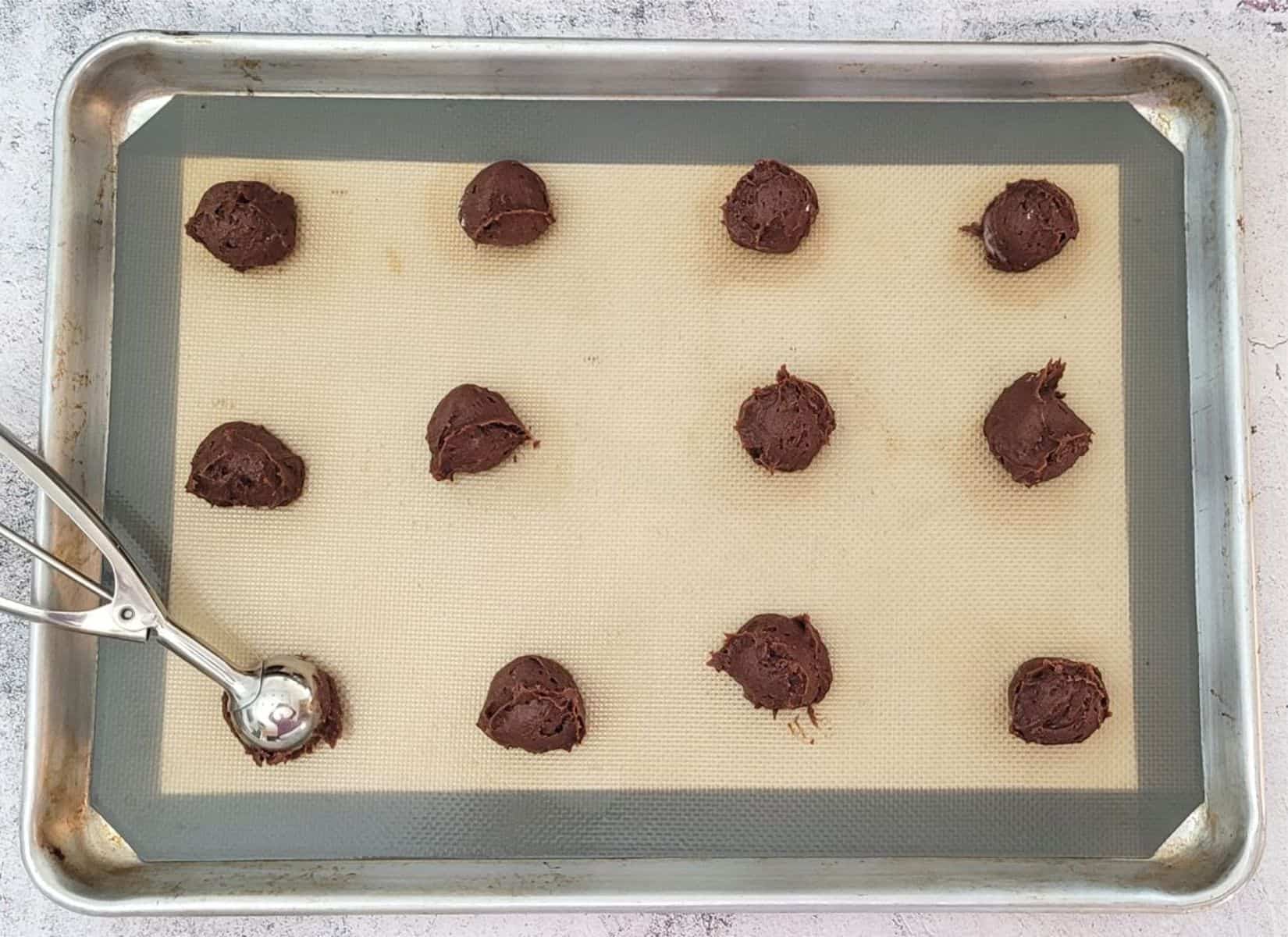 balls of cookie dough scooped onto a sheet pan for baking