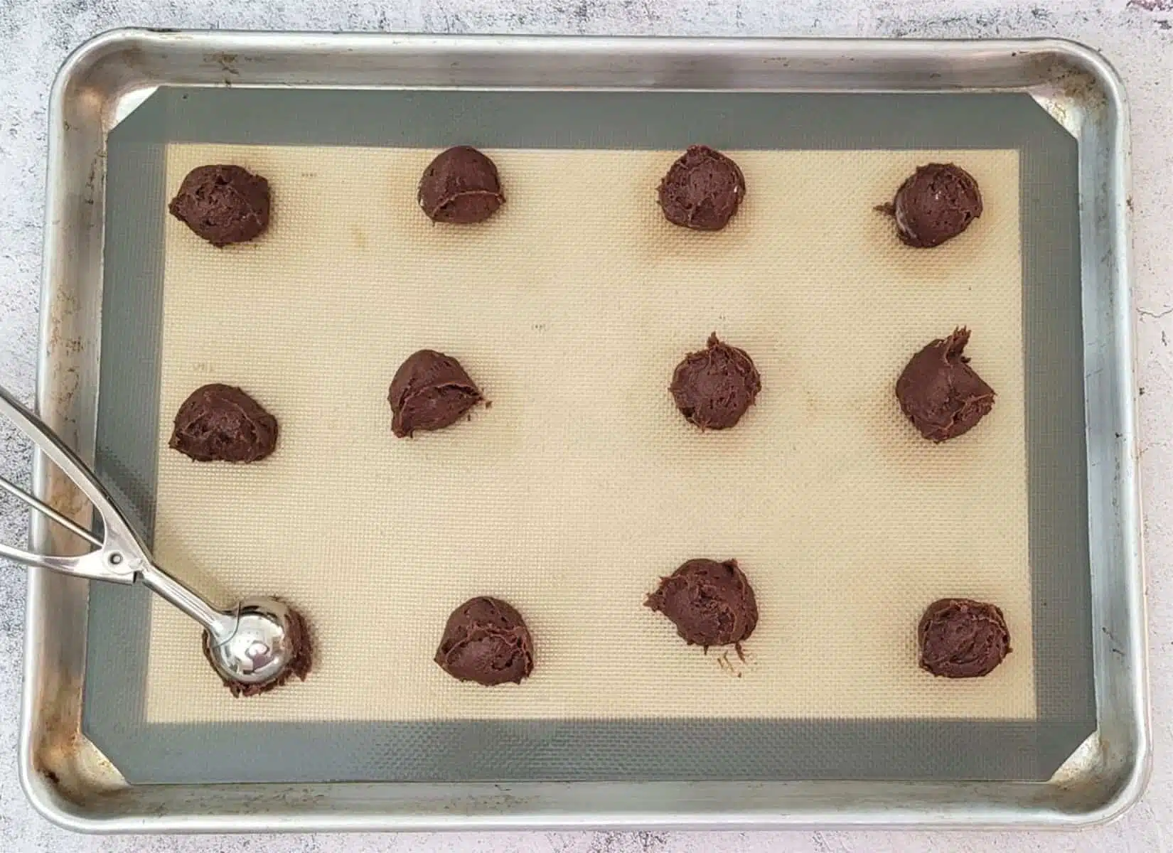 balls of cookie dough scooped onto a sheet pan for baking