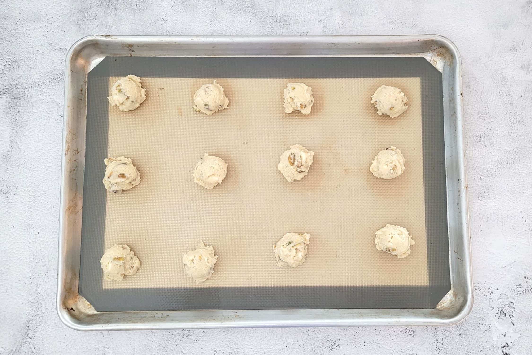 pistachio white chocolate cookie dough balls on a baking pan