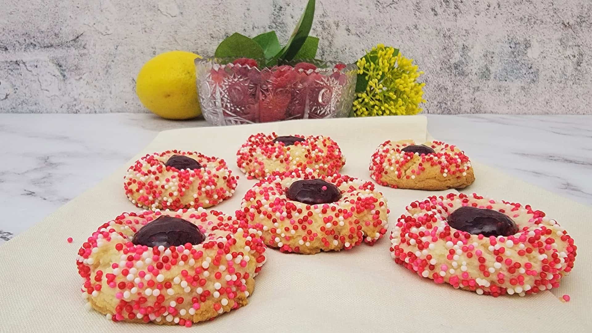 lemon cookies covered with sprinkles and filled with raspberry jam