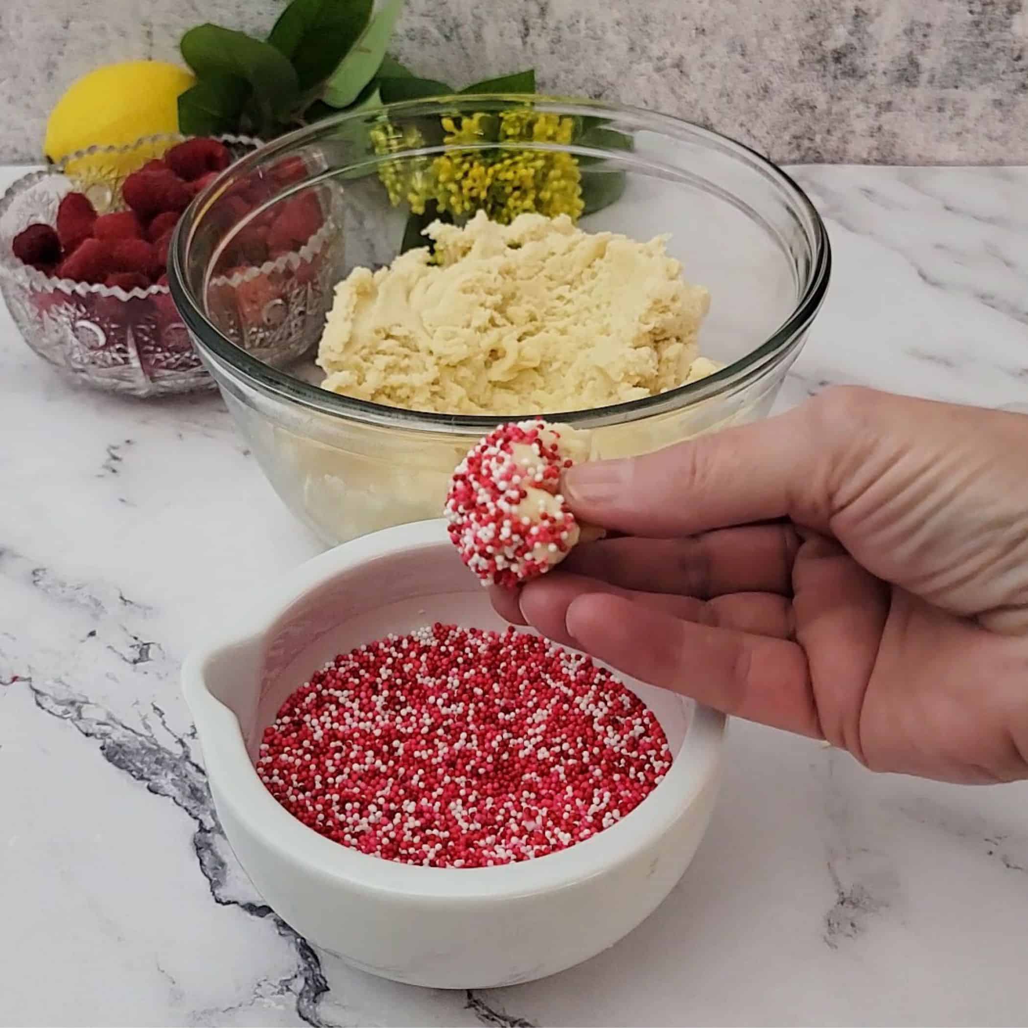 lemon cookie dough rolling in sprinkles before baking