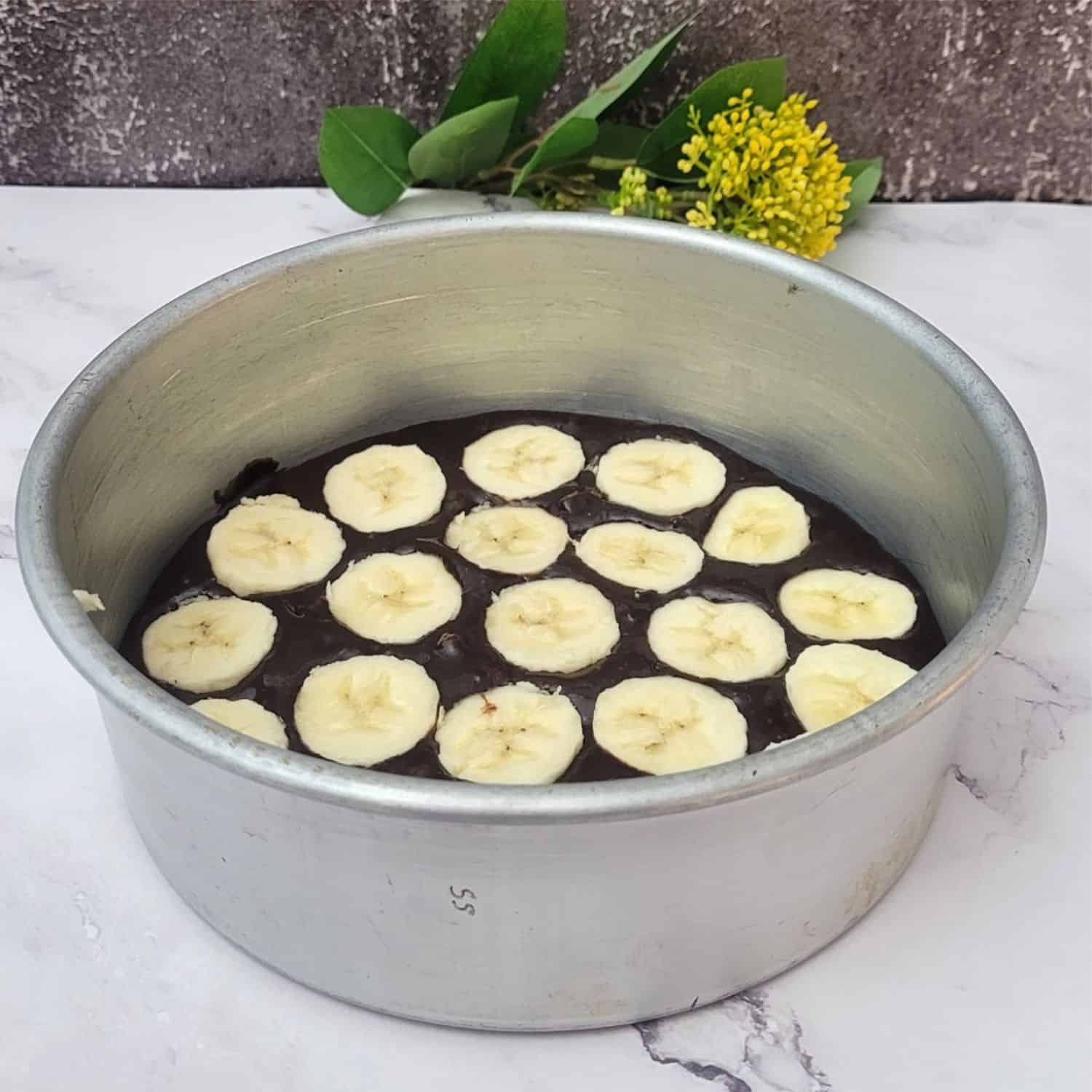 half of cake batter in baking pan topped with a layer of sliced bananas