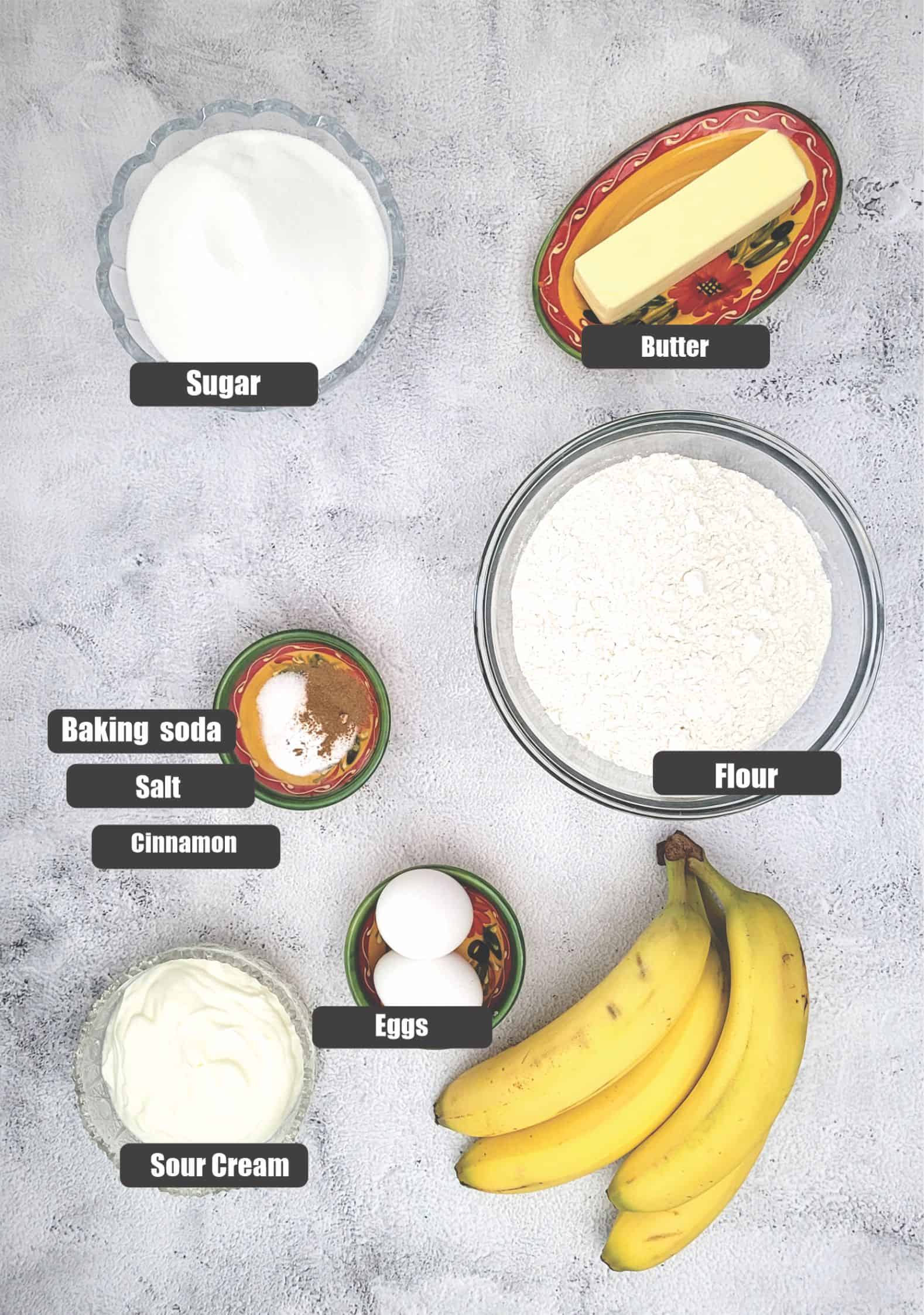 ingredients needed to make the Bundt cake including bananas, flour, baking soda, salt, cinnamon, eggs, sour cream, sugar and butter