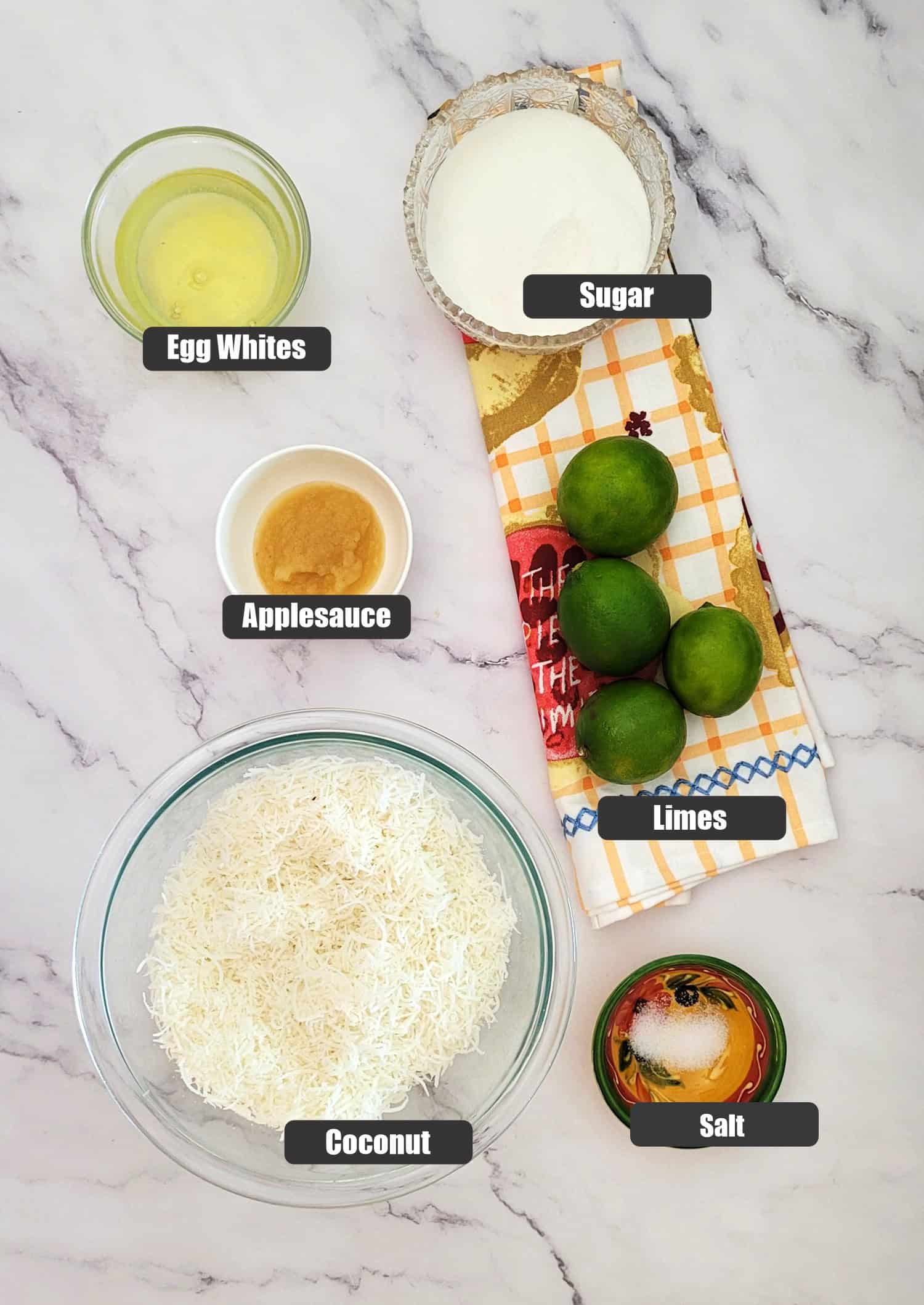 ingredients needed to make macaroons including shredded coconut, salt, egg whites, applesauce, sugar and limes