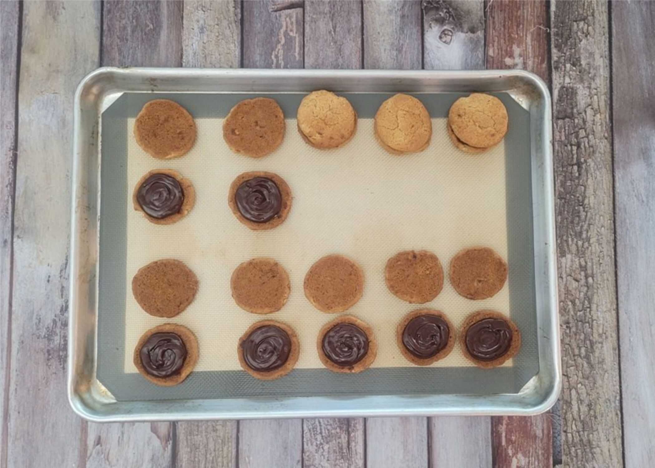 banana cookies on a sheet pan being filled with chocolate ganache