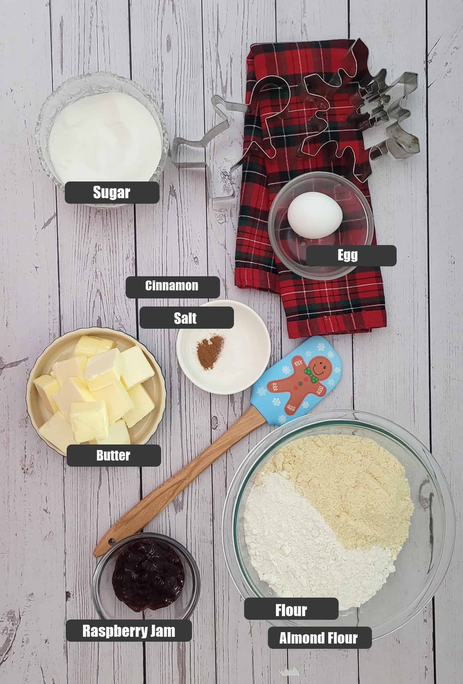 ingredients needed to make holiday Linzer cookies recipe including flour, almond flour, butter, raspberry jam, salt, cinnamon, an egg and granulated sugar