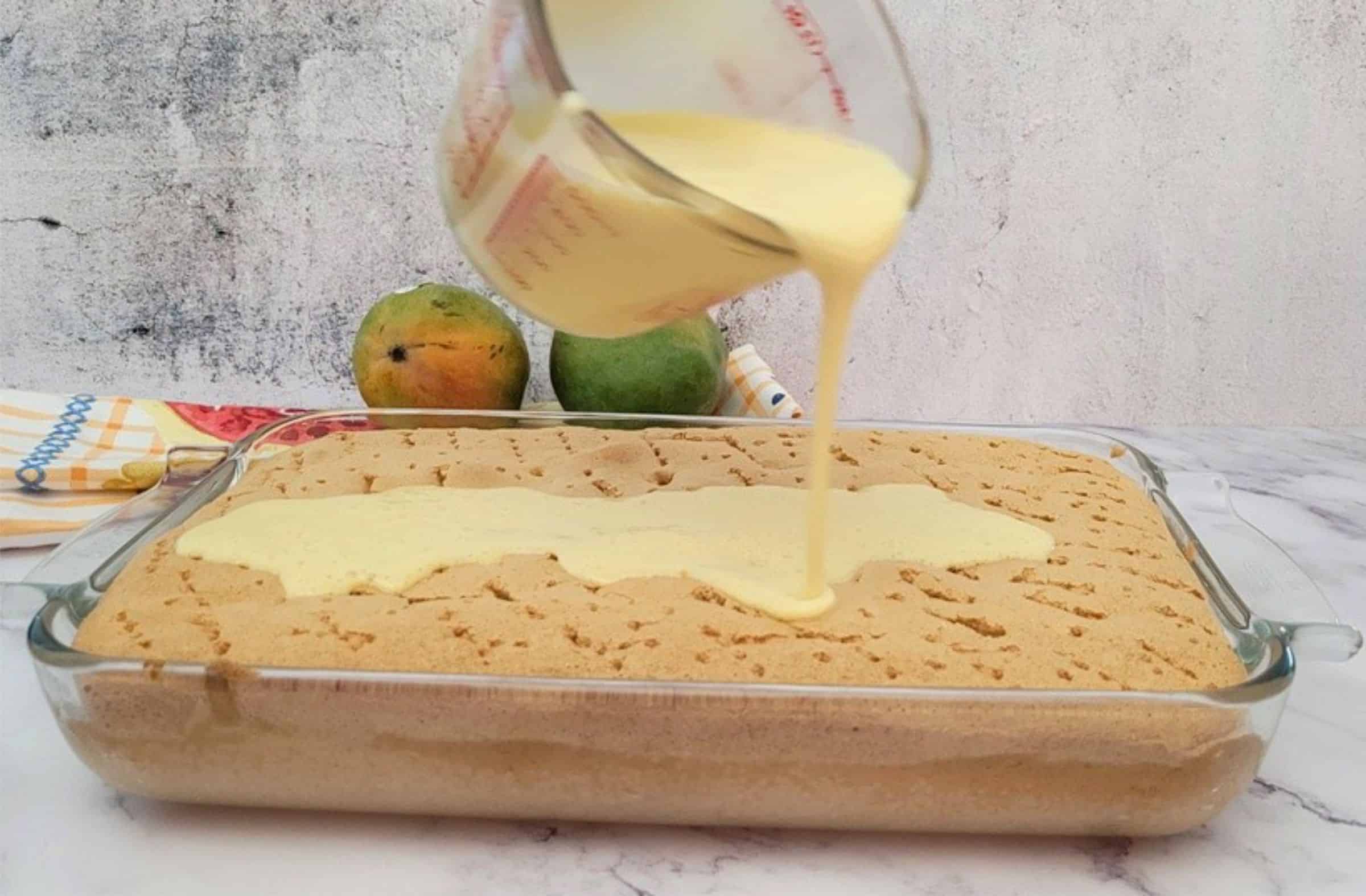 three milks and mango being poured over sponge cake to soak