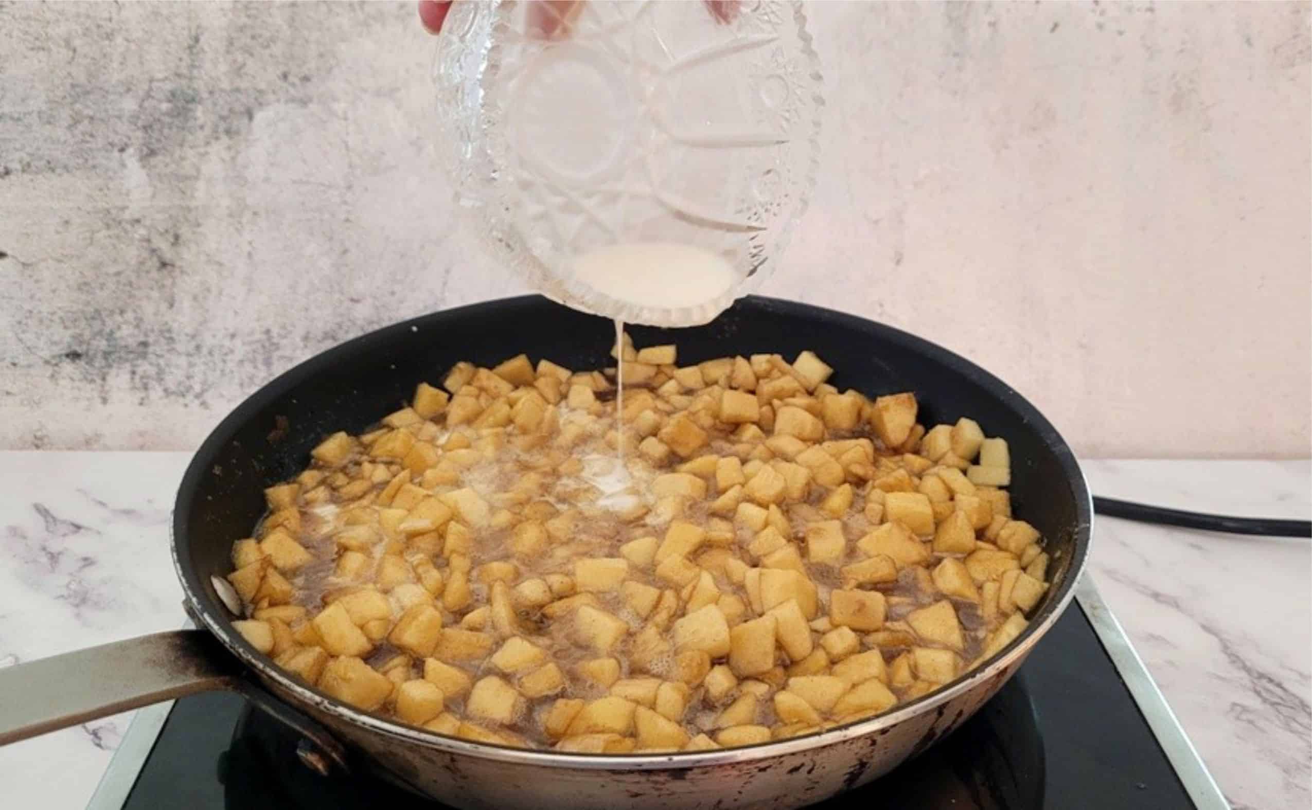 adding cornstarch to a saucepan with apples to thicken the filling