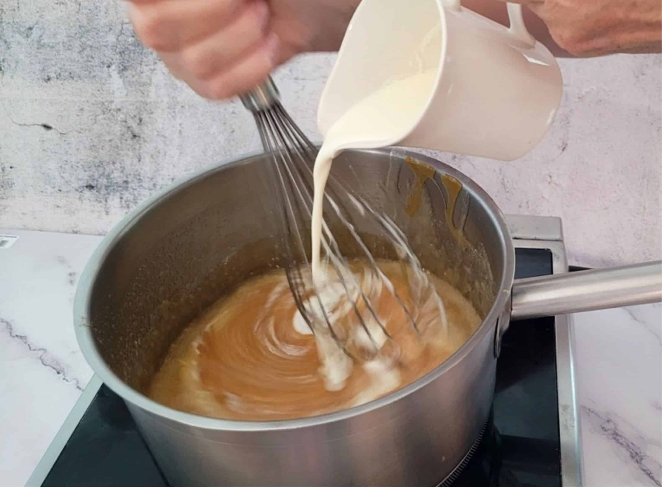 adding cream to saucepan with caramel sauce