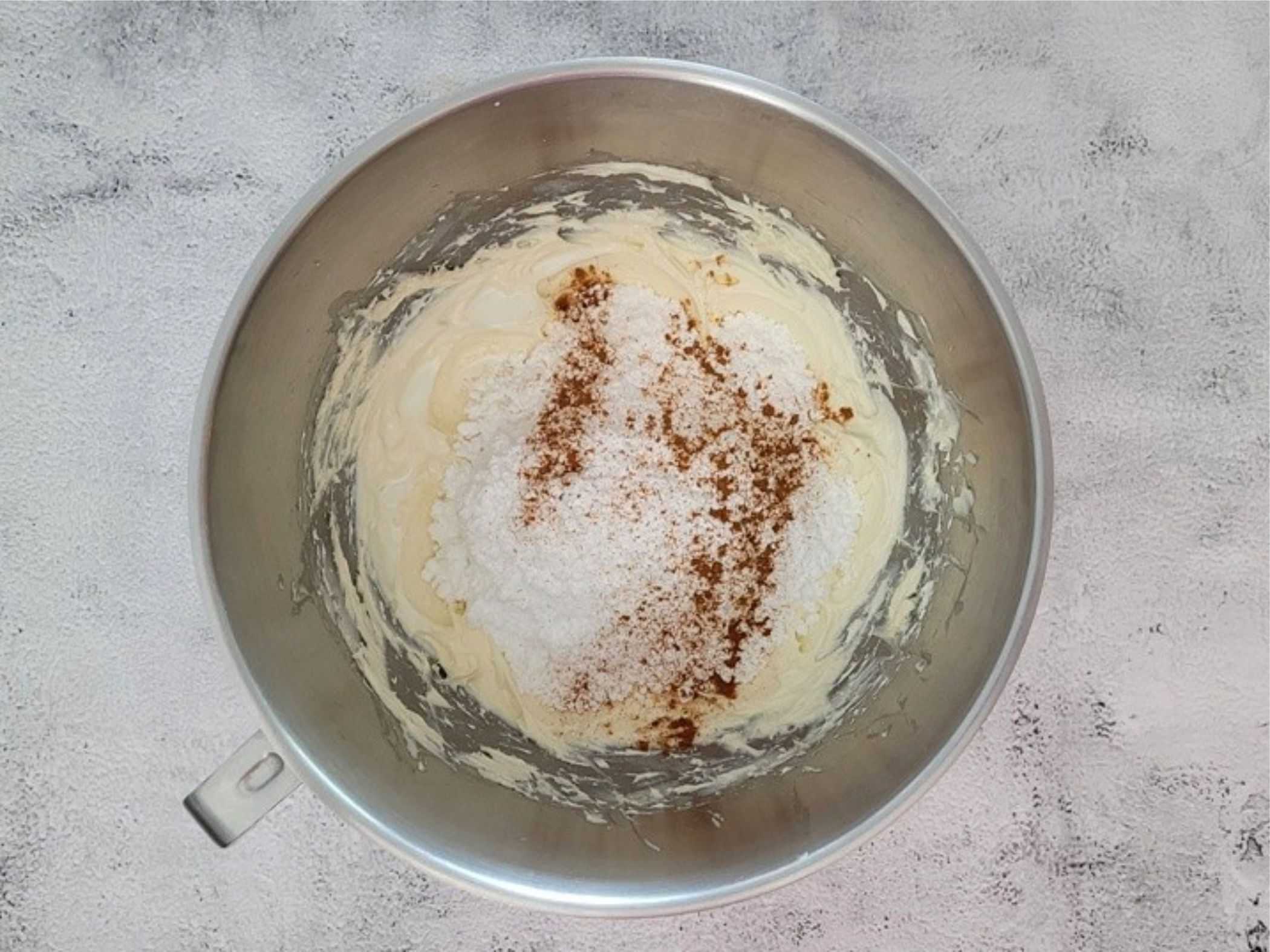 powdered sugar and cinnamon added to cream cheese and butter in mixing bowl