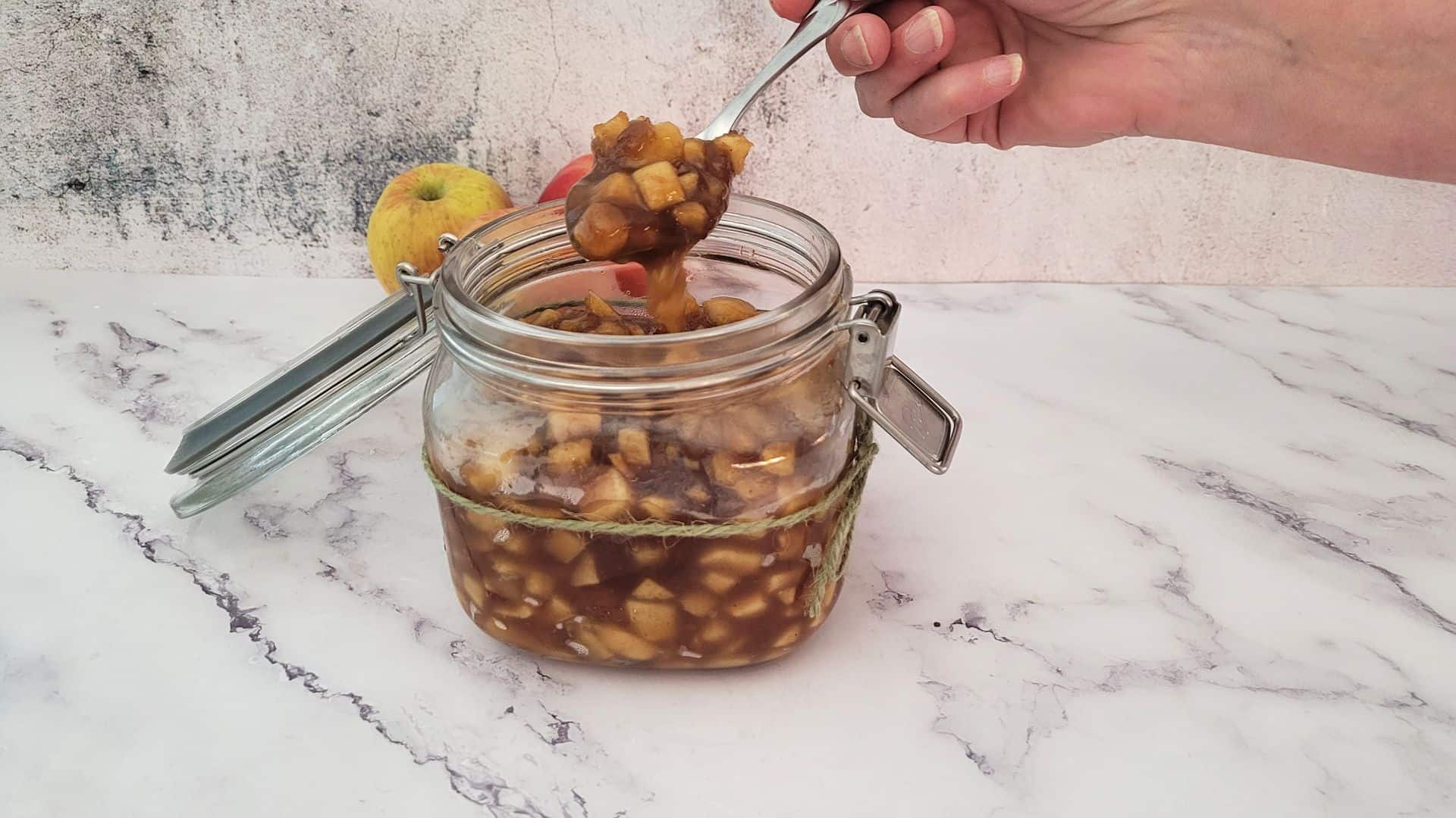 homemade apple filling in a jar with a spoonful showing