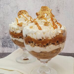 two parfaits layered with apple filling, whipped cream and granola