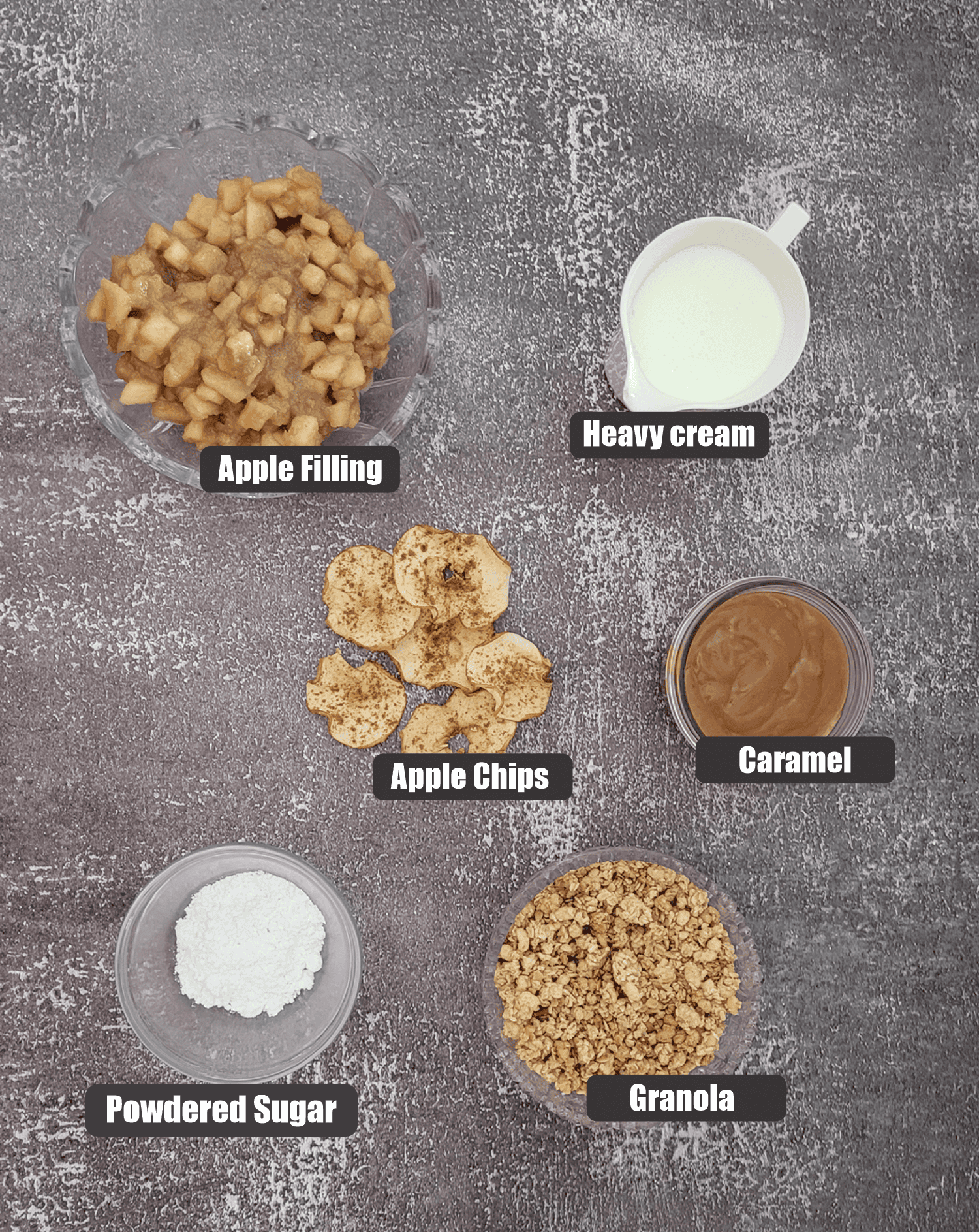 ingredients needed to make apple and granola parfaits including: granola, powdered sugar, apple chips, apple filling and heavy cream