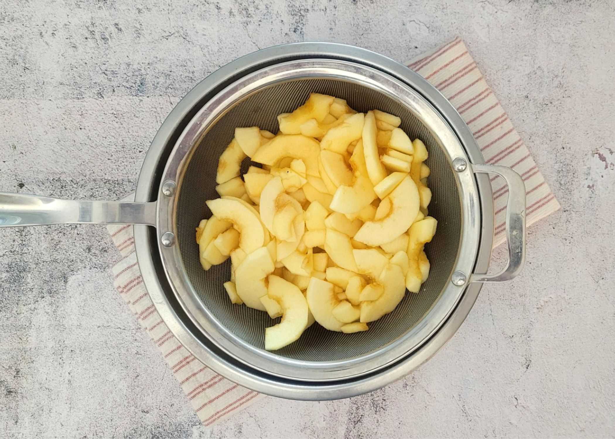 apple slices in a sieve to drain excess juices after macerating