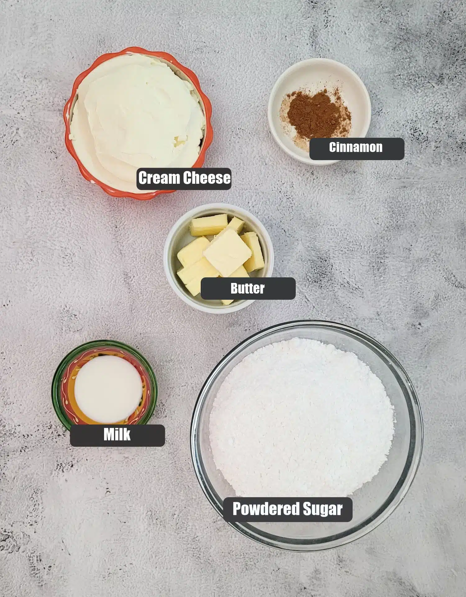 ingredients needed to make cinnamon cream cheese frosting including powdered sugar, butter, cream cheese, ground cinnamon and milk