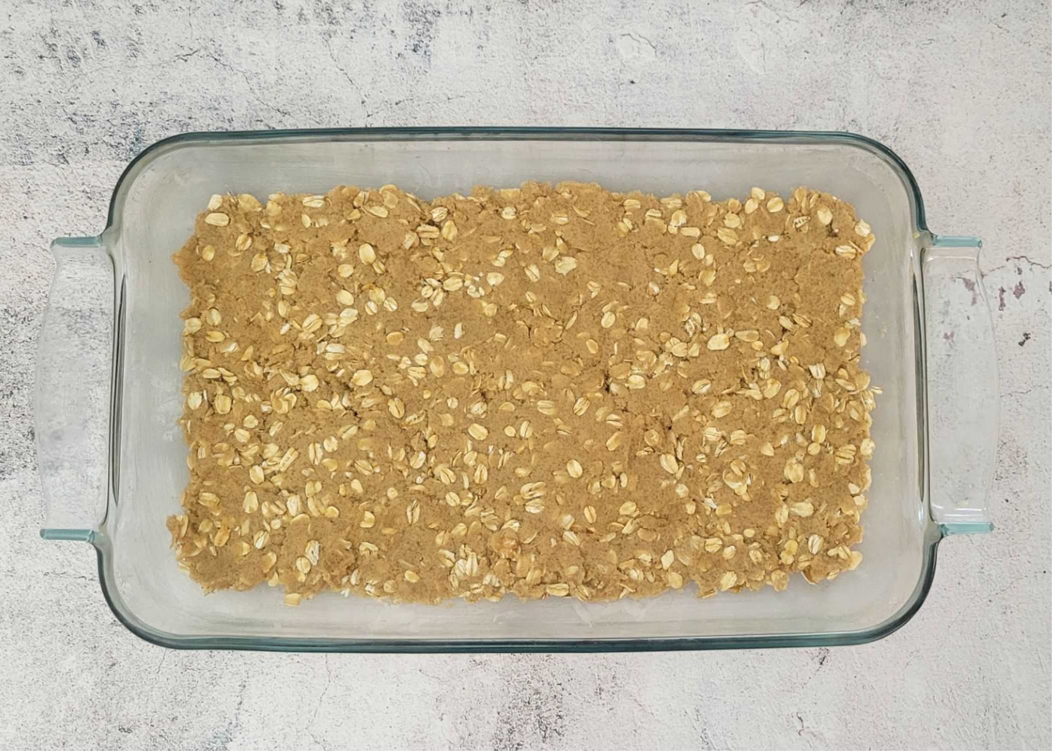 Bottom layer of oatmeal cookie dough pressed into a baking pan