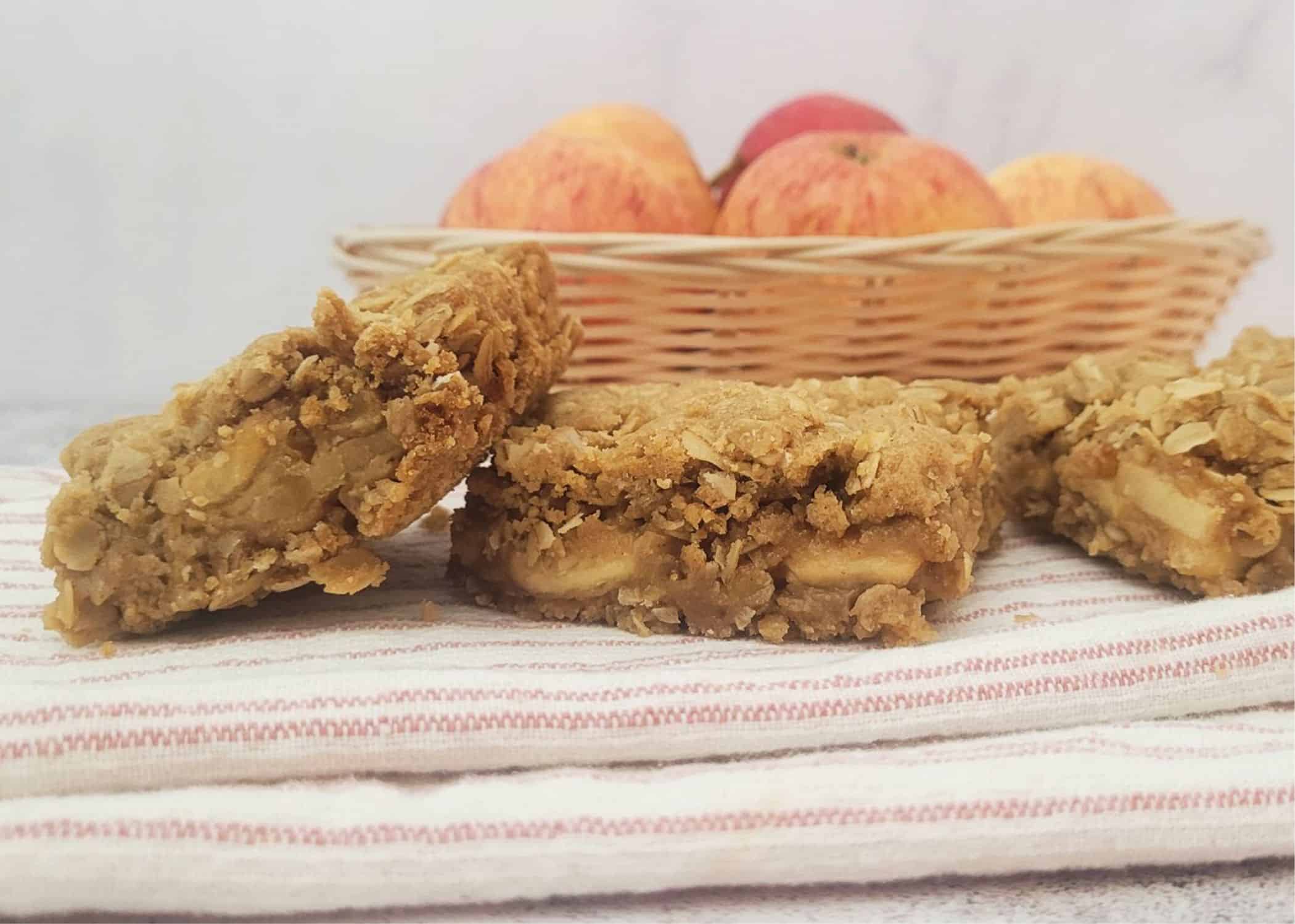 Finished Oatmeal apple bars on a napkin and apples in the background