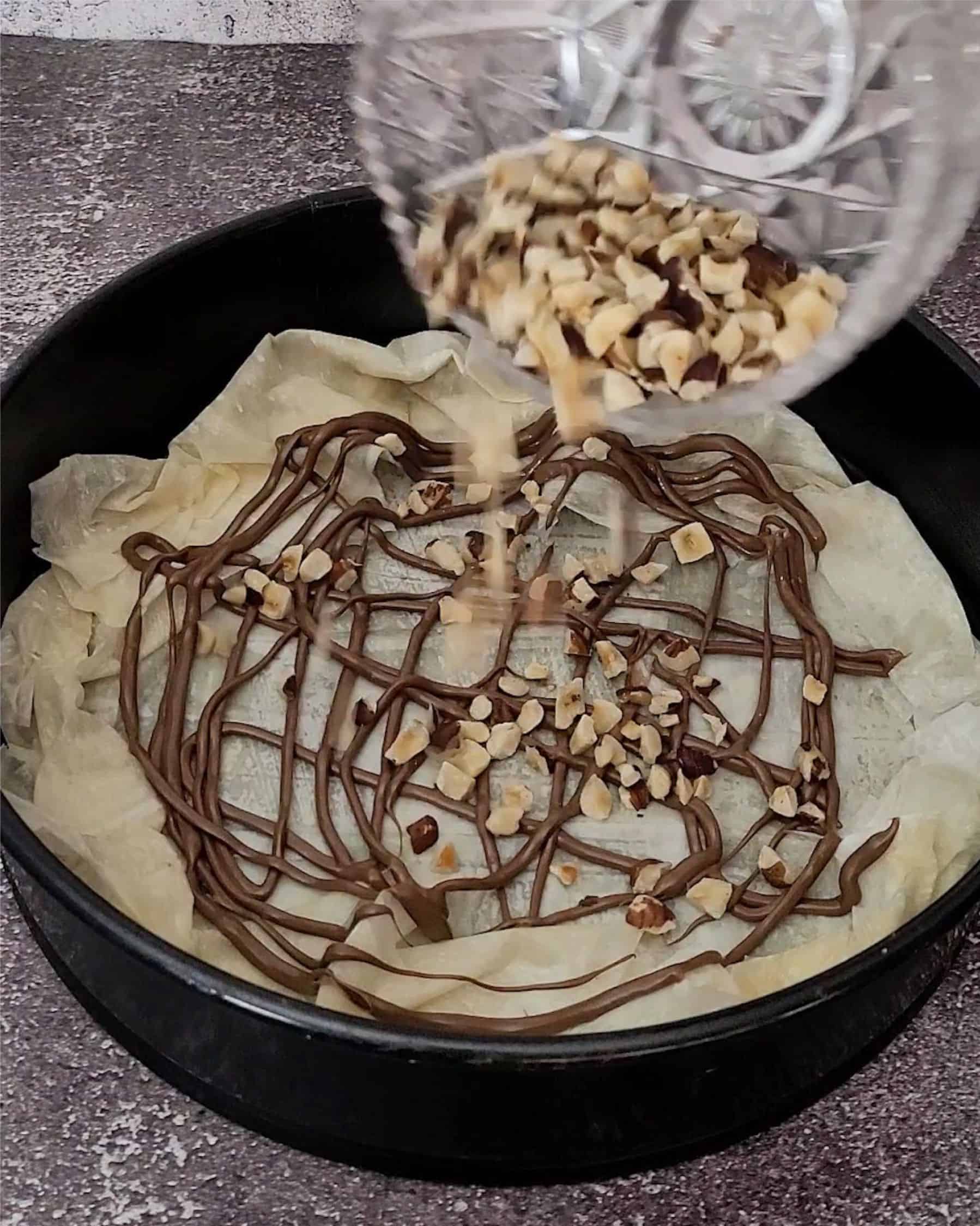 adding toasted hazelnut pieces to cake pan