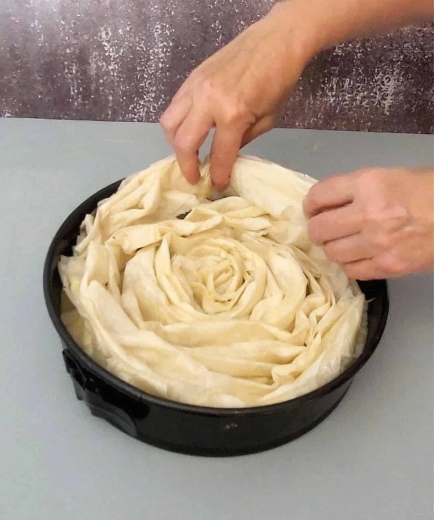 placing last layer of folded phyllo in cake pan