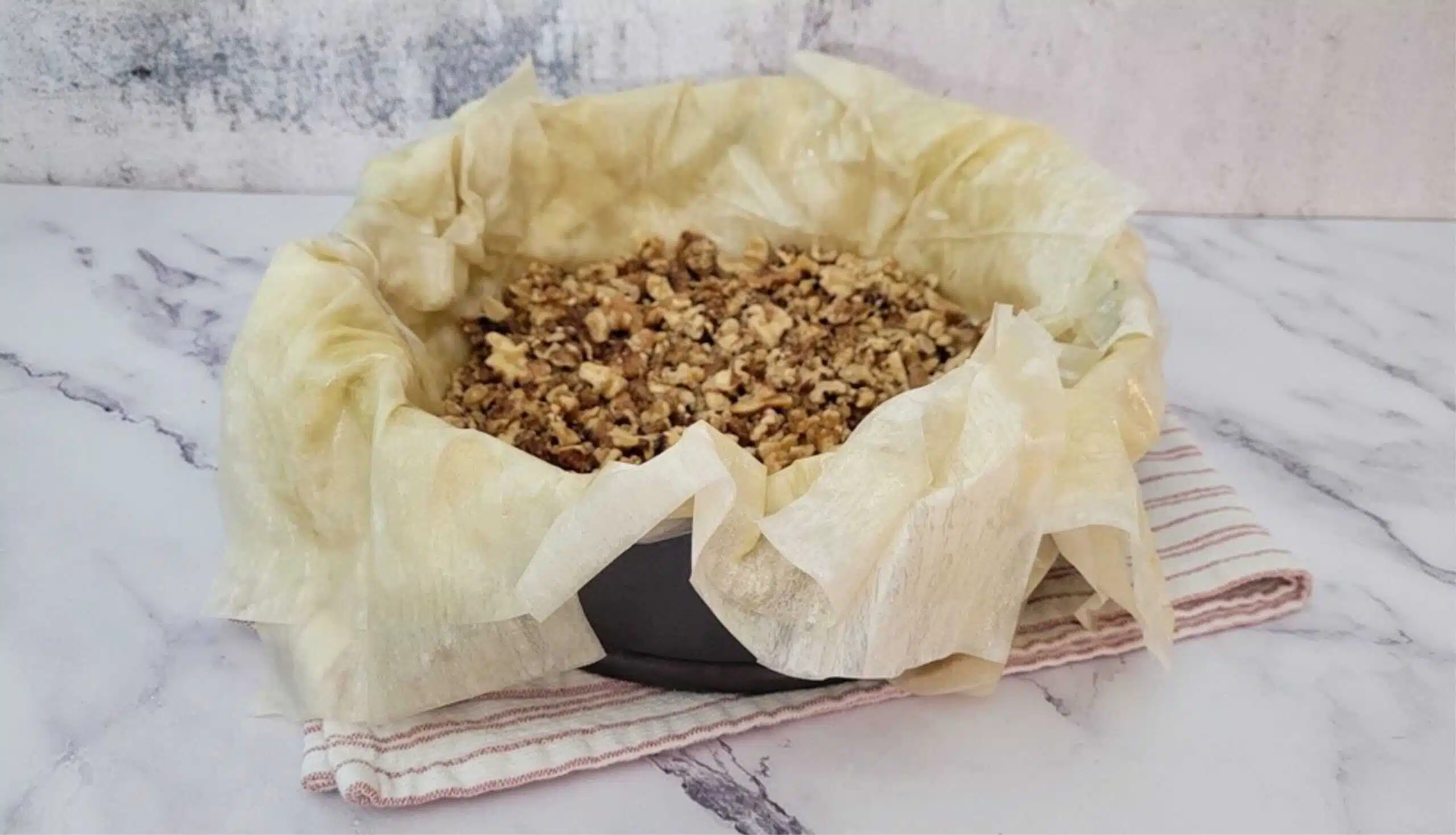 walnut and honey mixture added to baking pan on top of phyllo