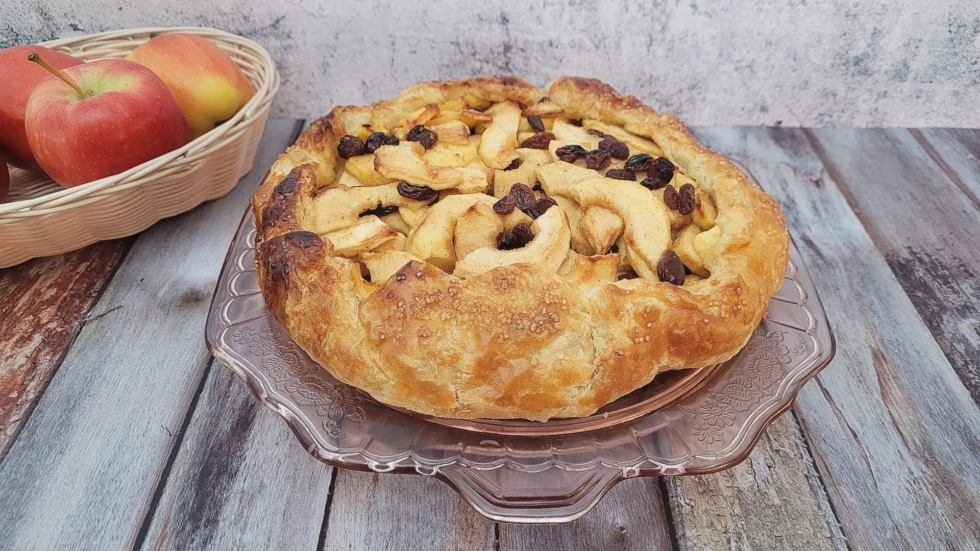 a rustic apple galette on a platter sitting on a wooden countertop