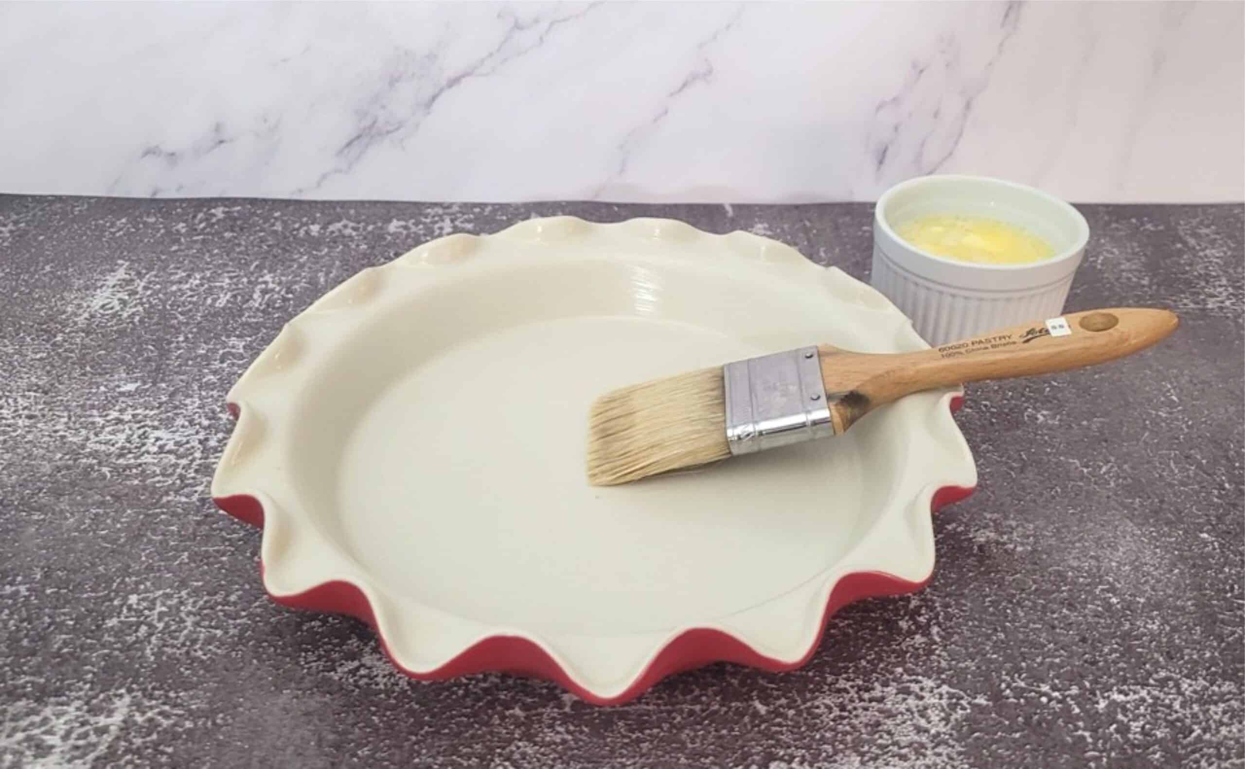 ceramic pie dish and a pastry brush for buttering pan