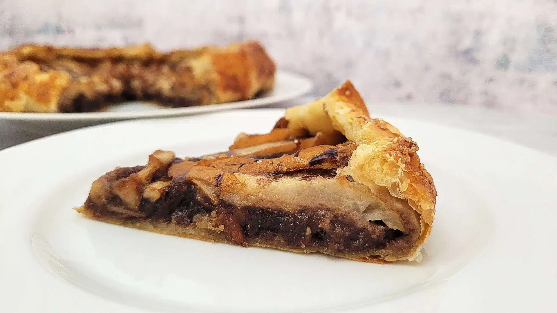 slice of chocolate pear galette with almonds on a plate and remainder of galette in background