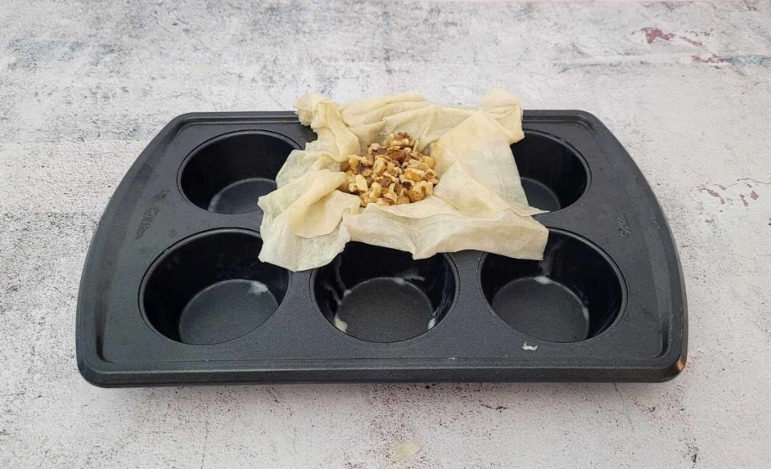 phyllo dough in a muffin tin with apples, walnuts and honey added to center