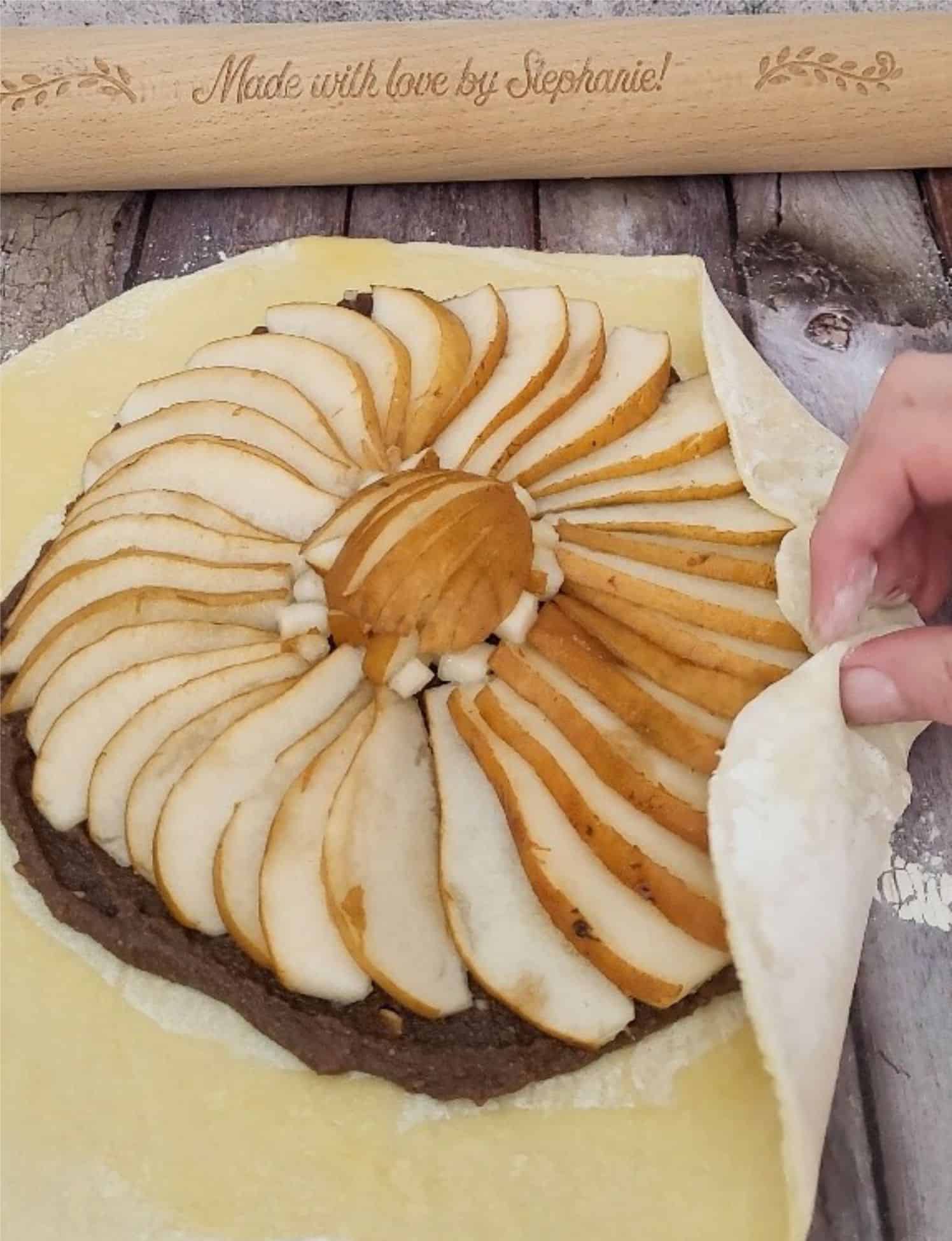 puff pastry being folded over fillings to make chocolate pear galette with almonds