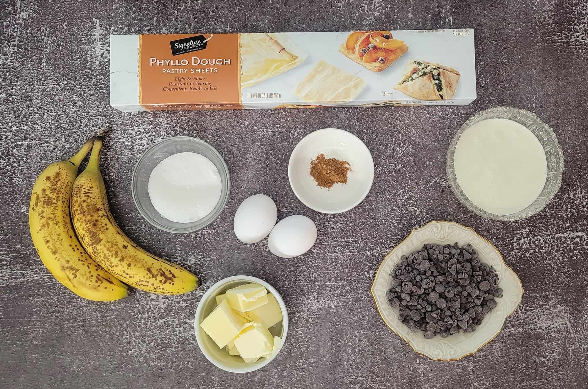 ingredients needed to make crinkle pie including phyllo dough, bananas, sugar, eggs, cinnamon, butter, heavy cream and chocolate