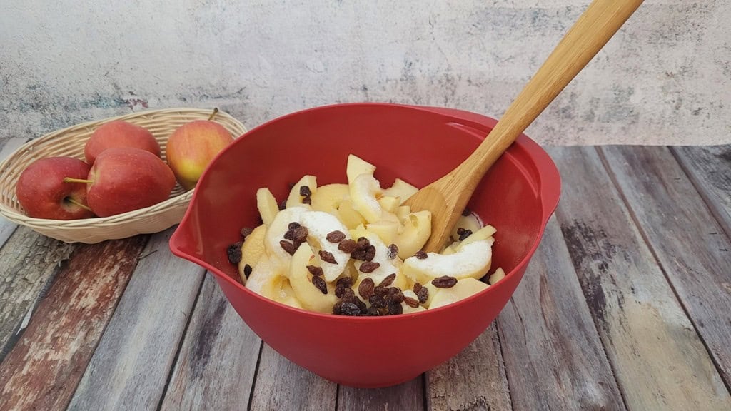 apples and raisins in a bowl with sugar added to start macerating