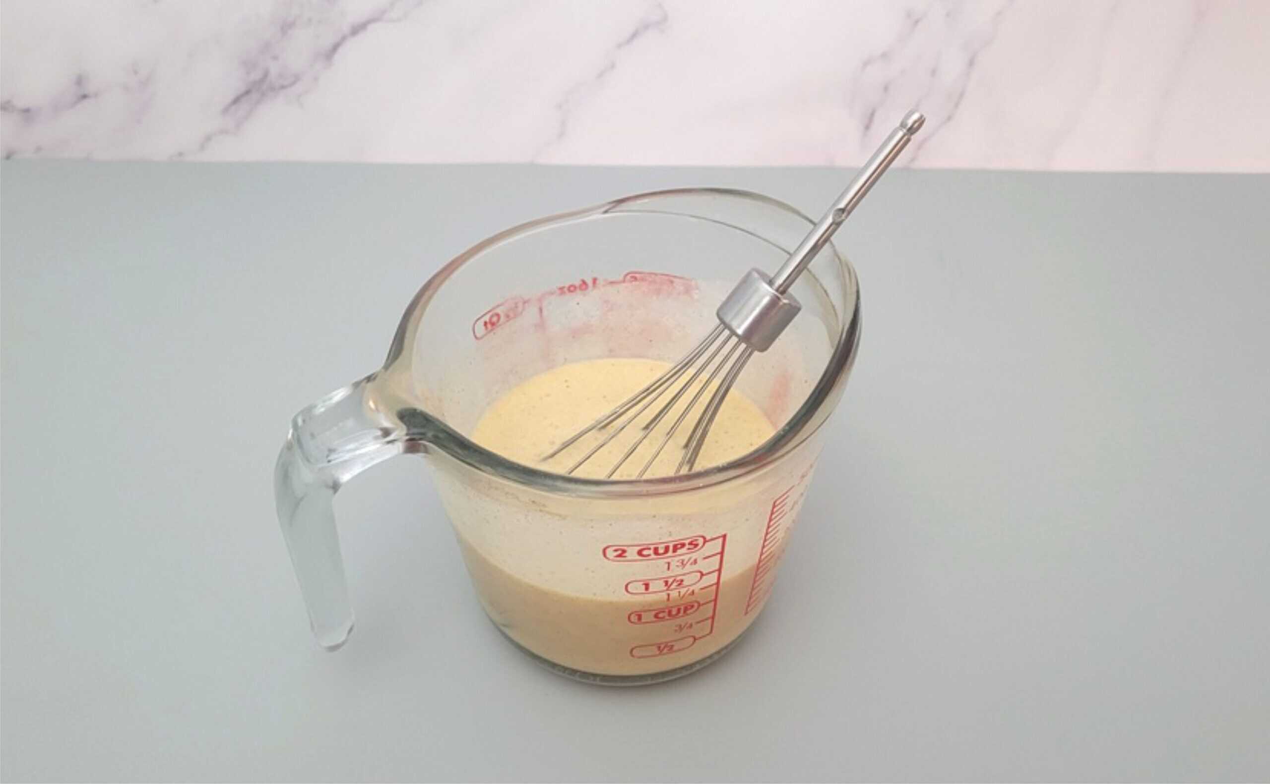 whisk and measuring cup with custard filling mixed together