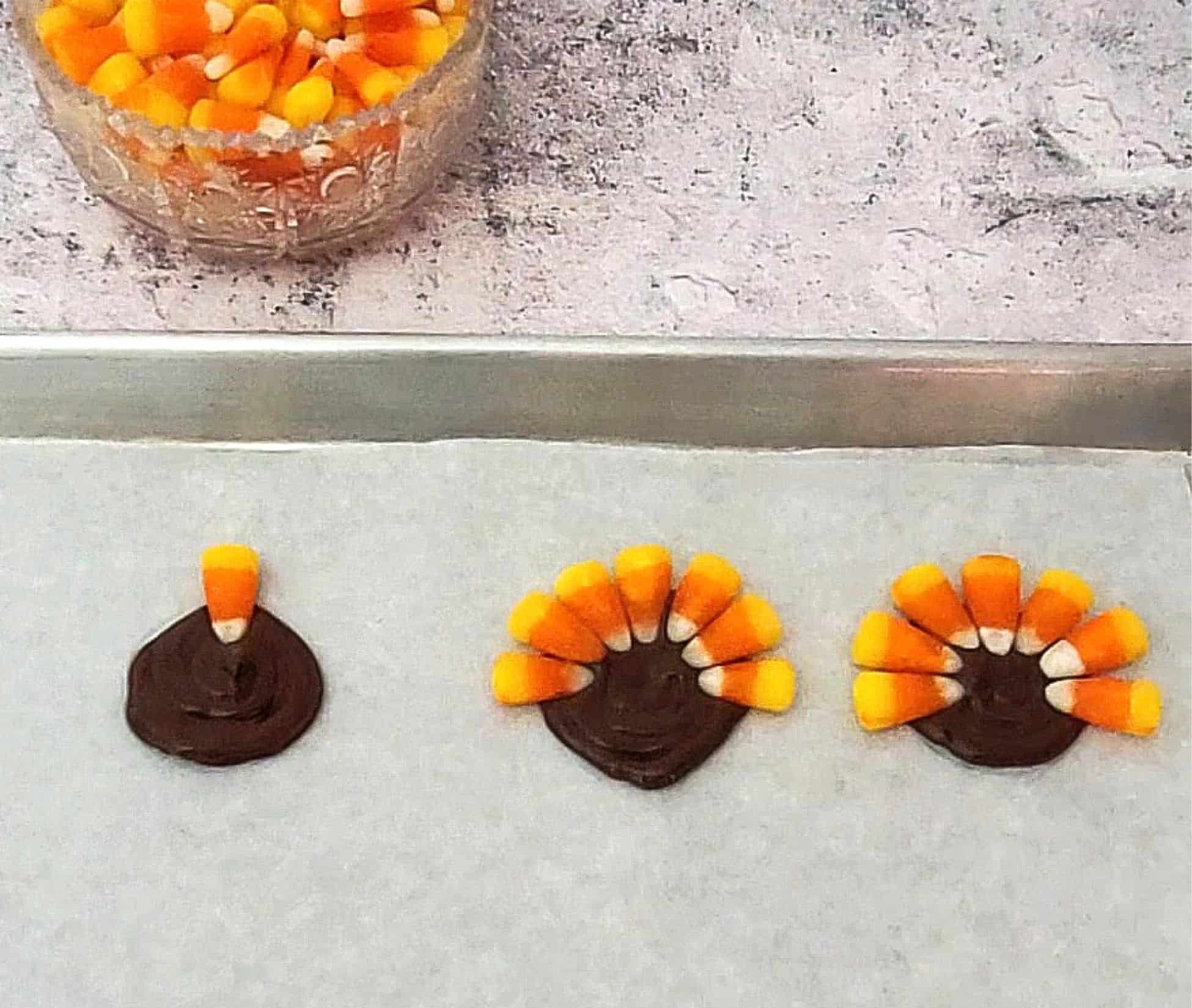 chocolate circles piped onto parchment paper and candy corns inserted in chocolate to feathers