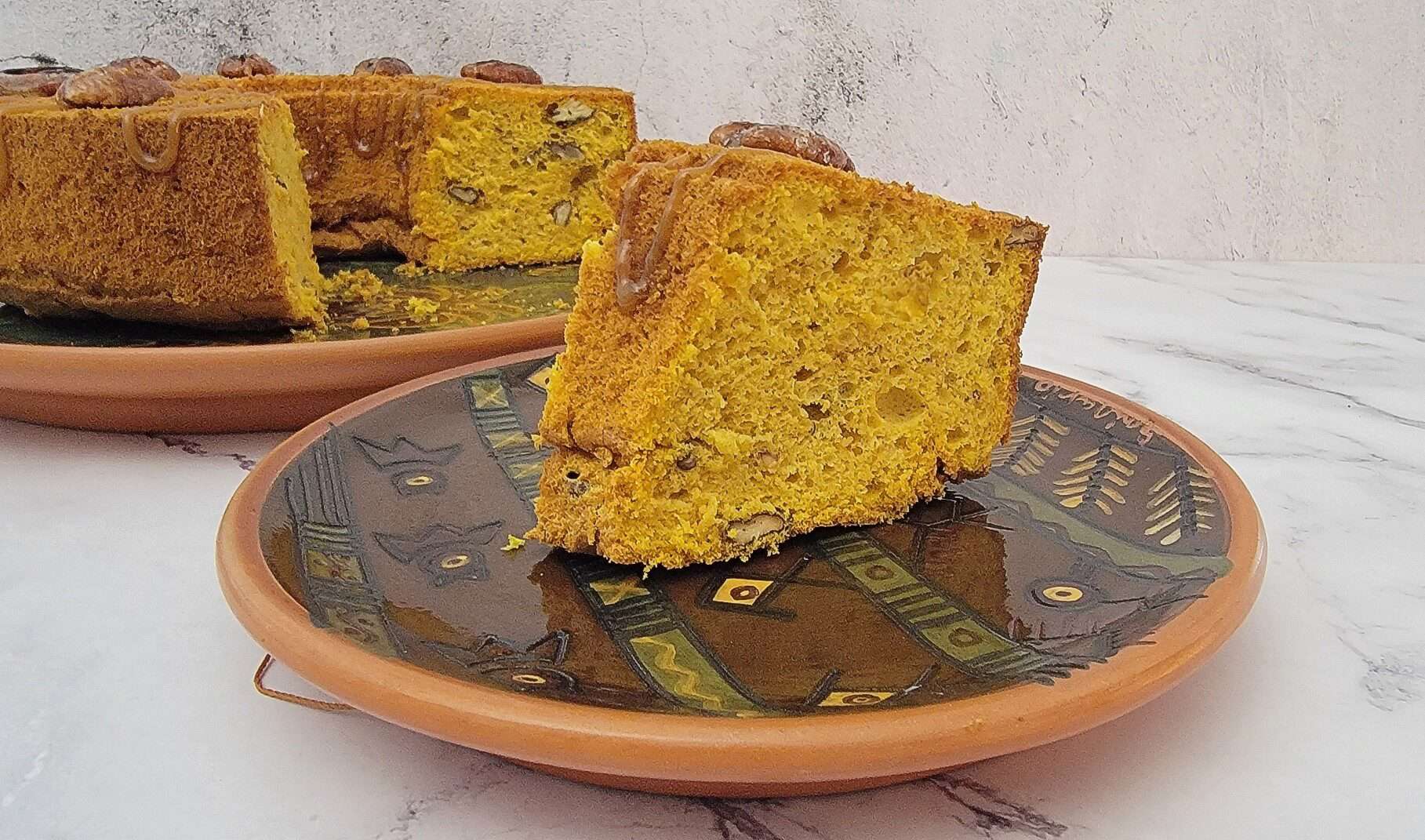 slice of pumpkin chiffon cake on a platter and the remainder of the cake in the background