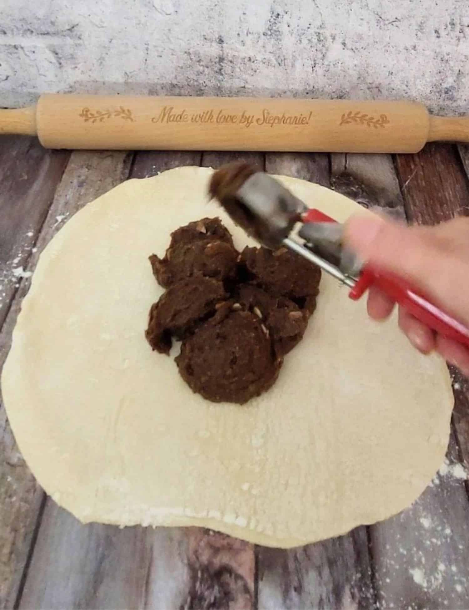 rolled out puff pastry circle with chocolate filling being added