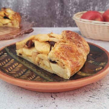 slice of apple galette on a plate with remainder of dessert in the background