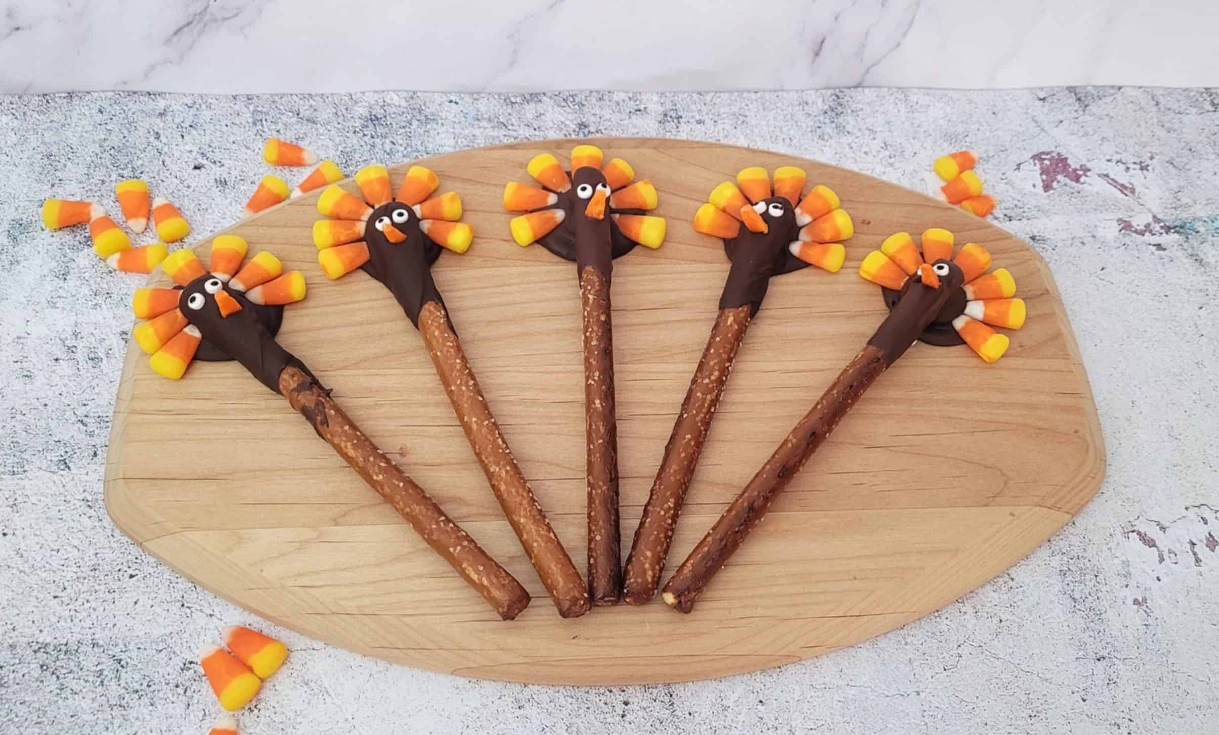 several pretzel rods decorated like turkeys using candy corn pieces for feathers