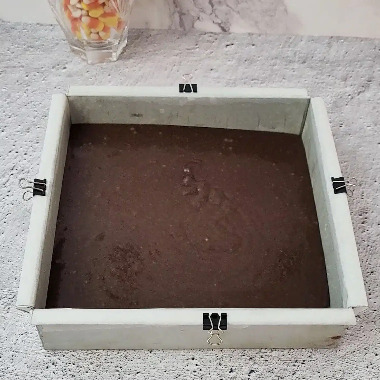 brownie batter poured into square baking pan