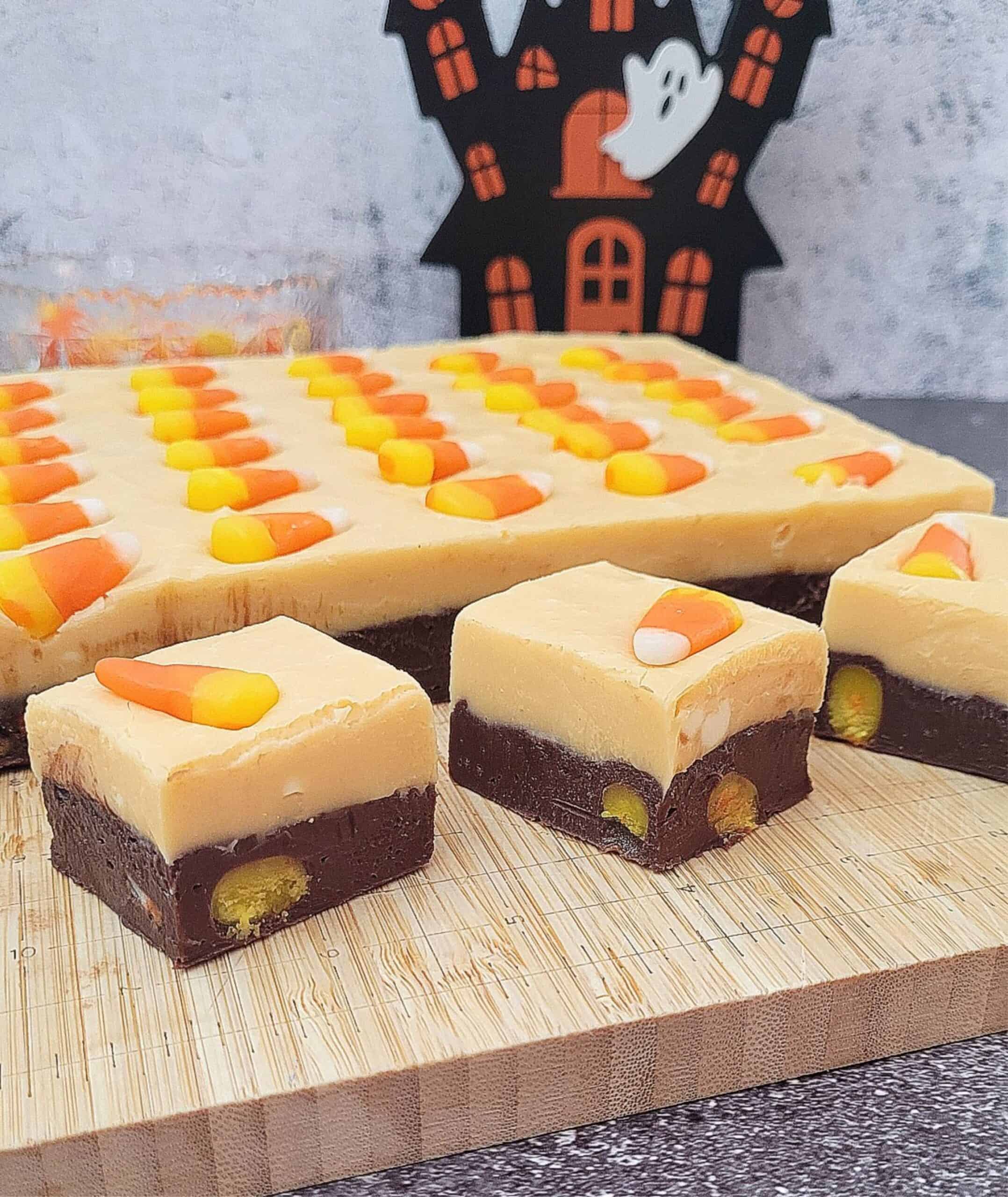 slab of fudge with an orange layer and a chocolate layer on a cutting board