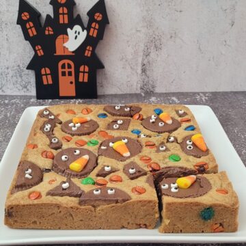 Halloween brown butter blondies and a haunted house in the background