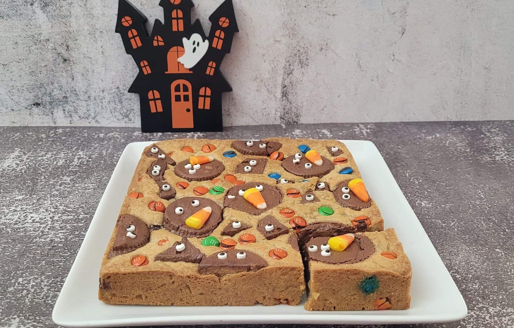 Halloween brown butter blondies and a haunted house in the background