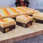 slab and pieces of Halloween candy corn fudge on a wooden cutting board