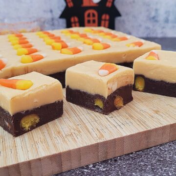 slab and pieces of Halloween candy corn fudge on a wooden cutting board