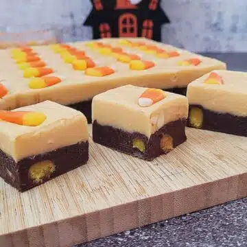 slab and pieces of Halloween candy corn fudge on a wooden cutting board