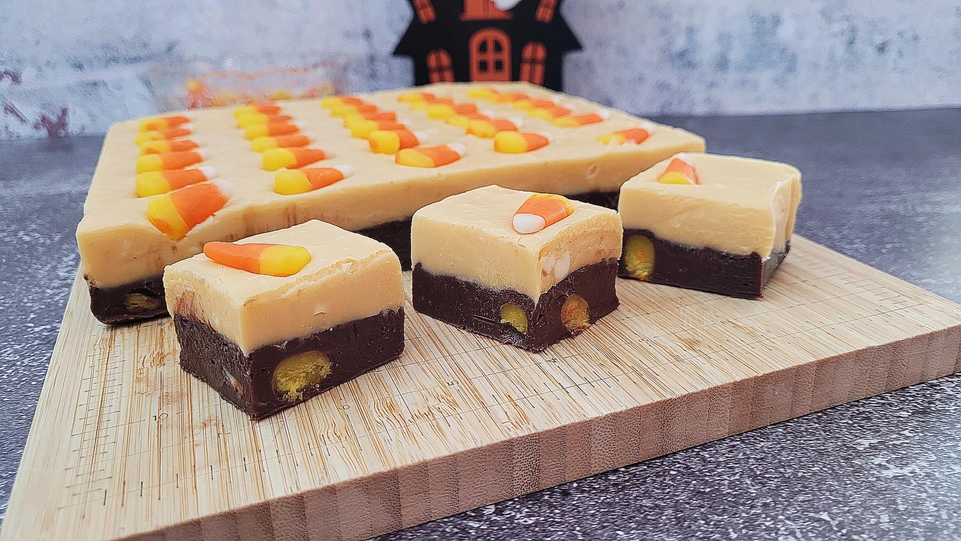 slab and pieces of Halloween candy corn fudge on a wooden cutting board