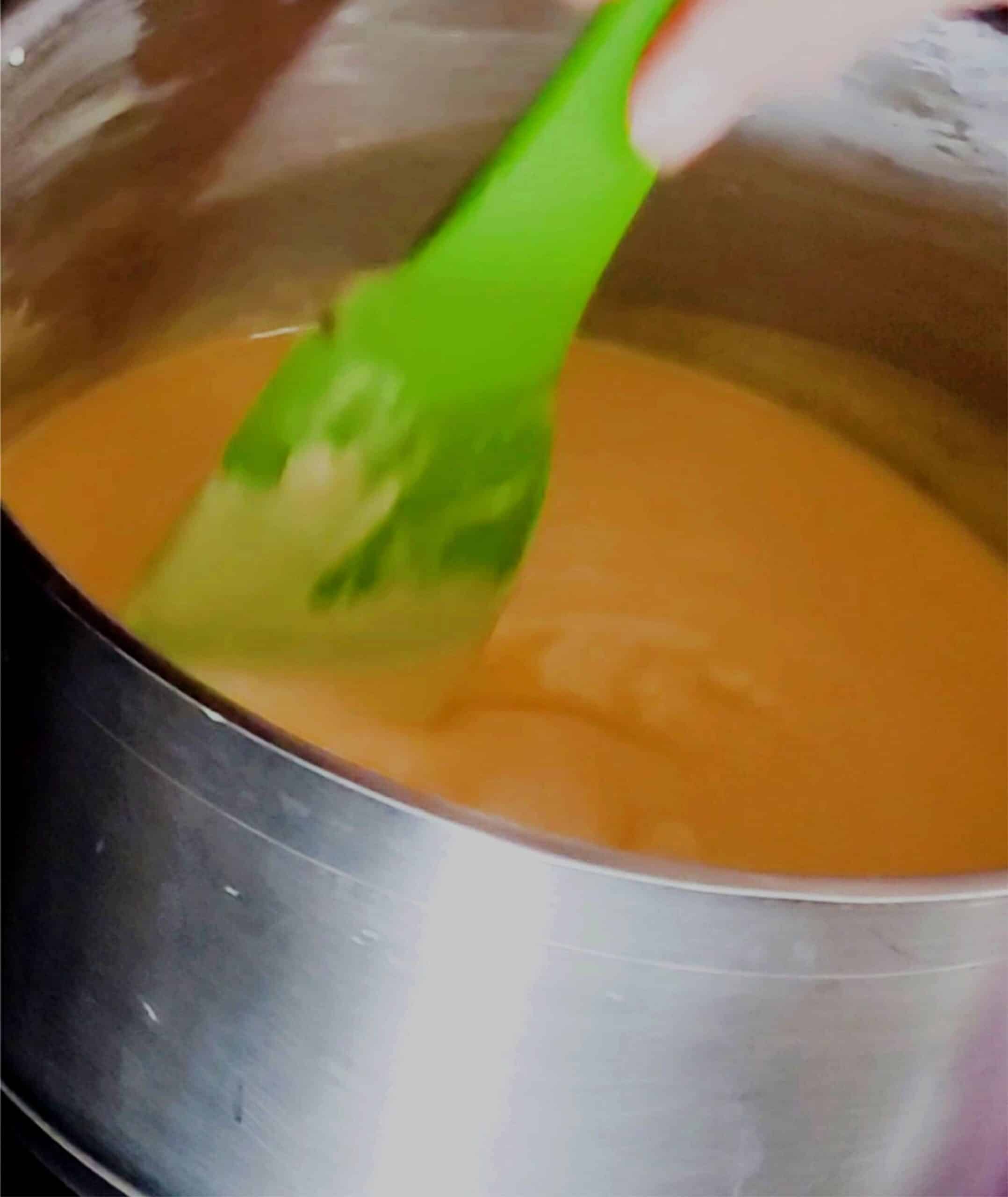 stirring together white chocolate chips, sweetened condensed milk and orange food coloring in a saucepan