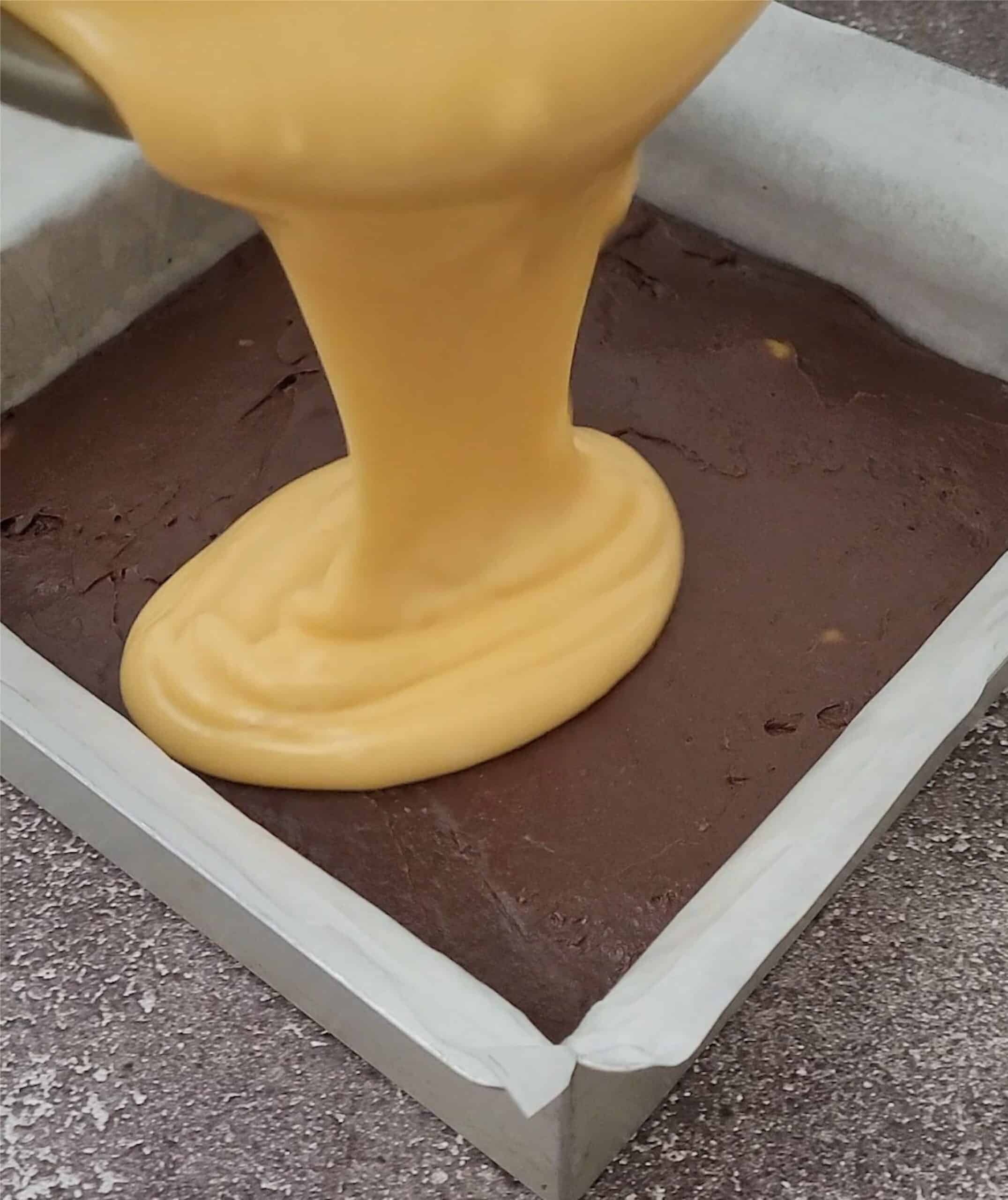 pouring orange fudge over chocolate fudge to make layered fudge