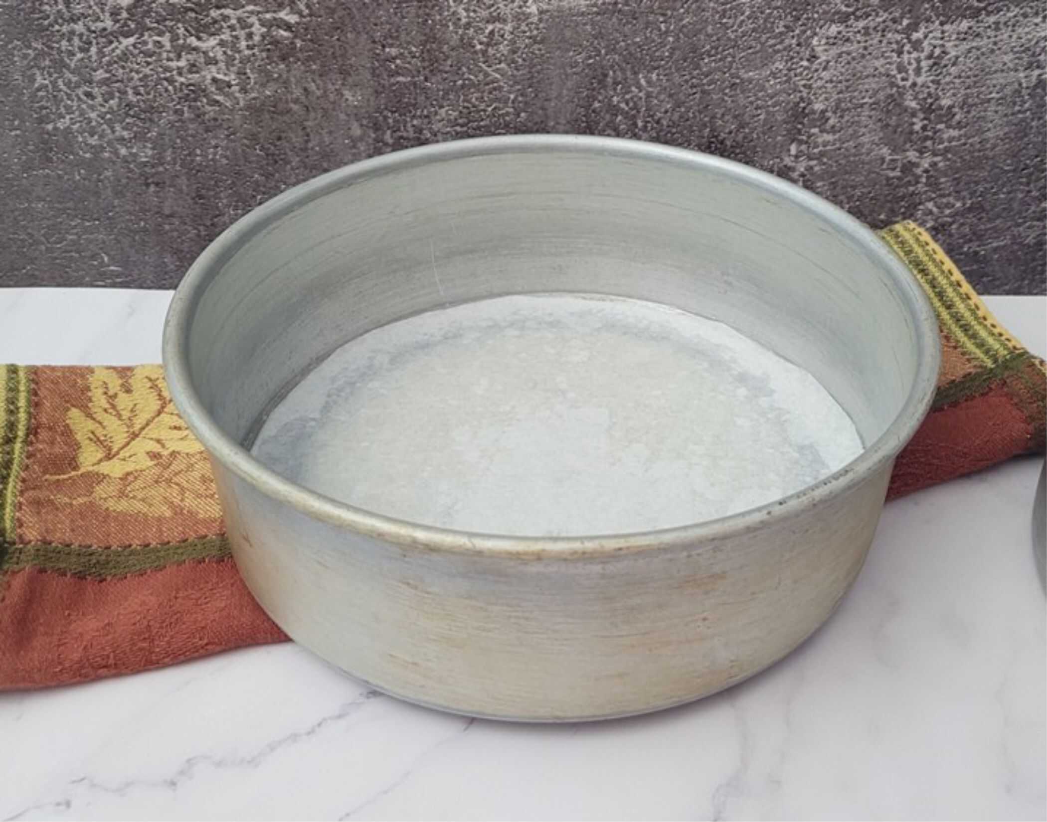 round cake pan with piece of parchment paper to prepare for baking